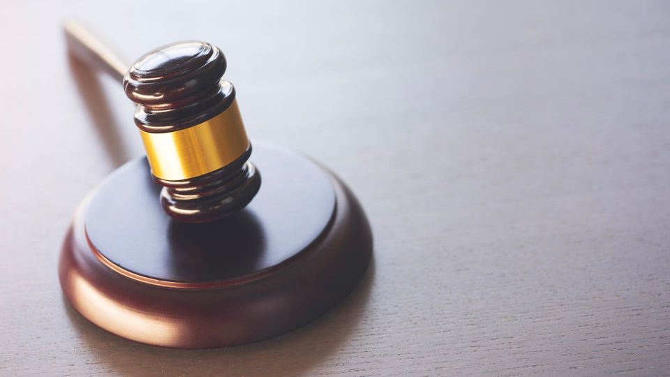 Close-up of a black and gold judge’s gavel on a matching round base
