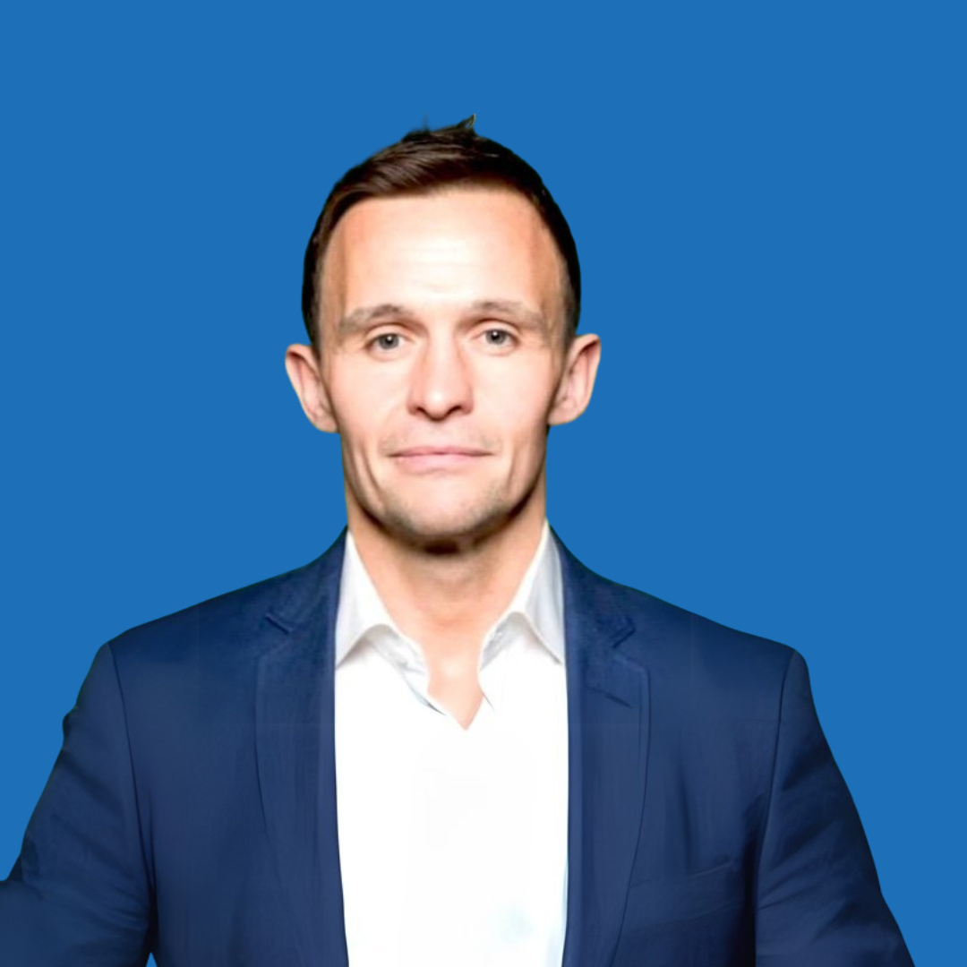 Man in a blue blazer and white shirt against a blue background, looking forward.