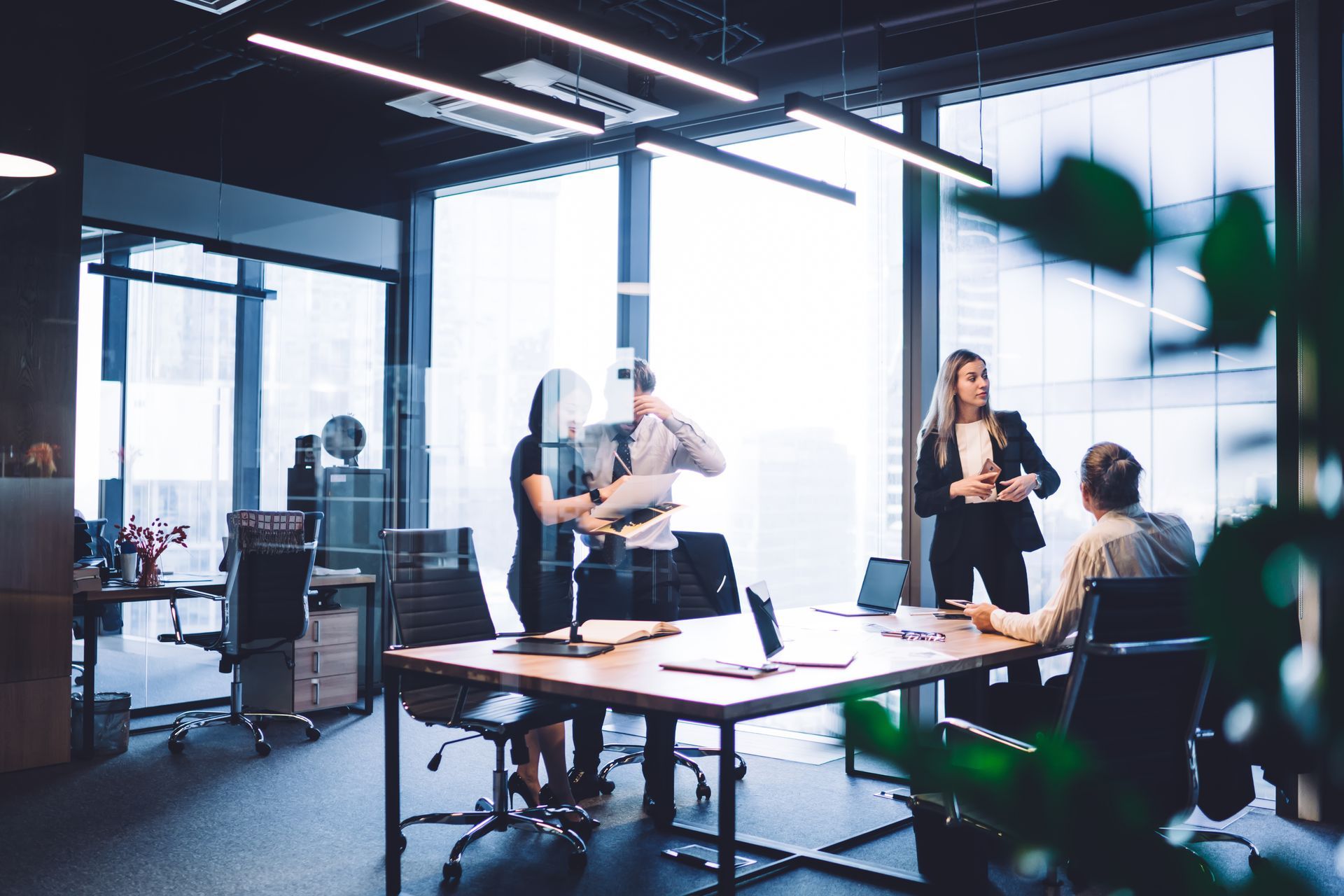 A group of people are sitting at a table in an office having a meeting.