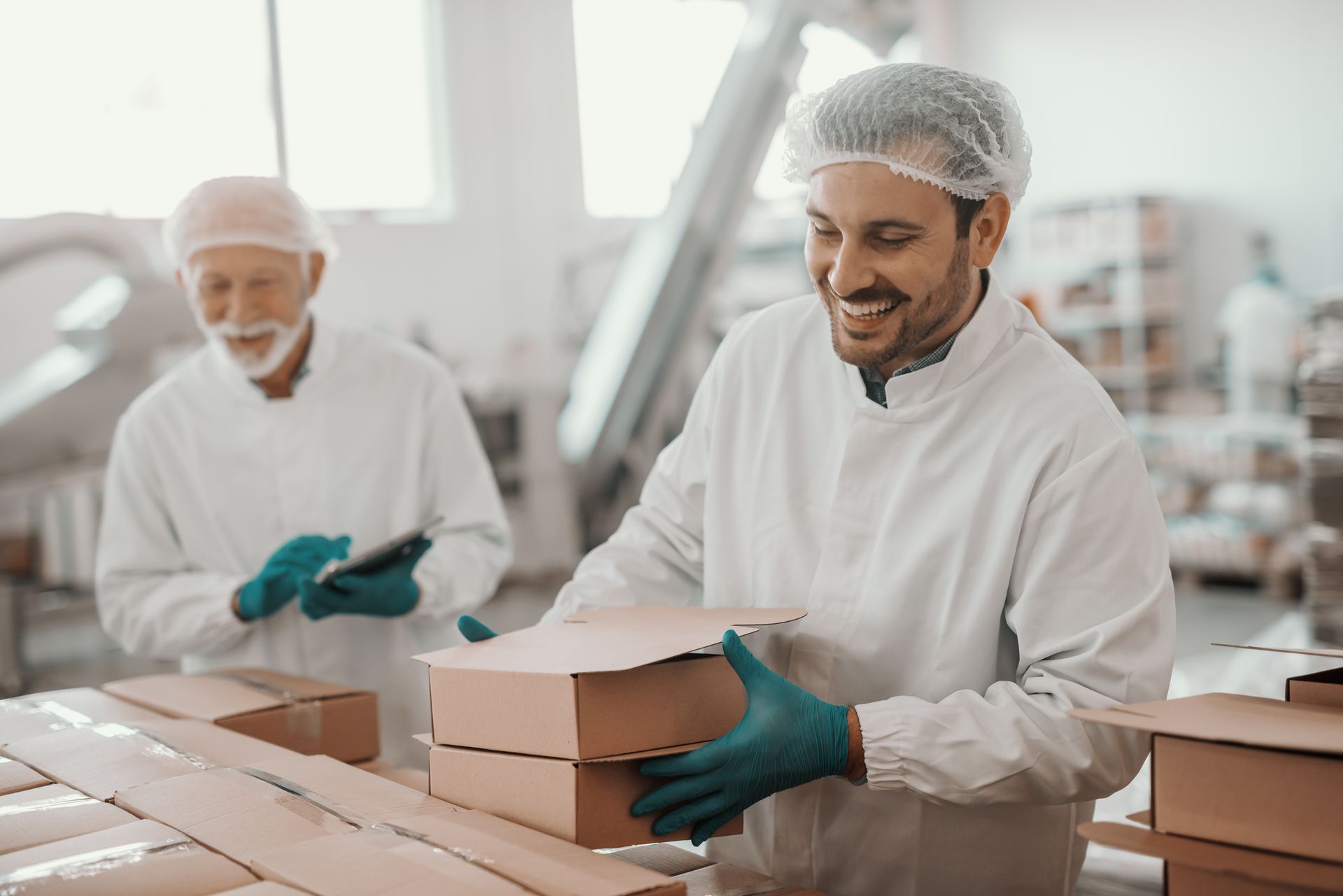 Two men are working in a factory packing boxes.