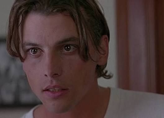 Close-up of a Skeet Ulrich in scream wearing a white shirt, looking concerned indoors