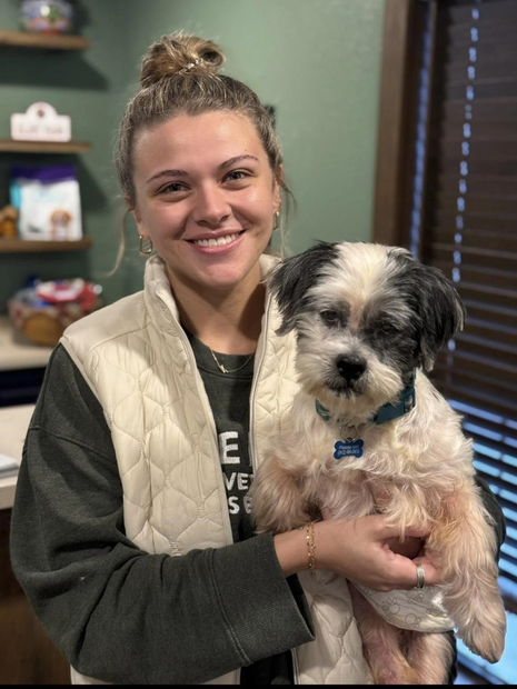 Smiling woman holding a small white-and-black dog indoors
