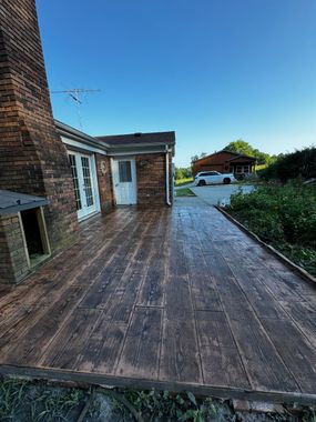 A brick house with a driveway that looks like wood.