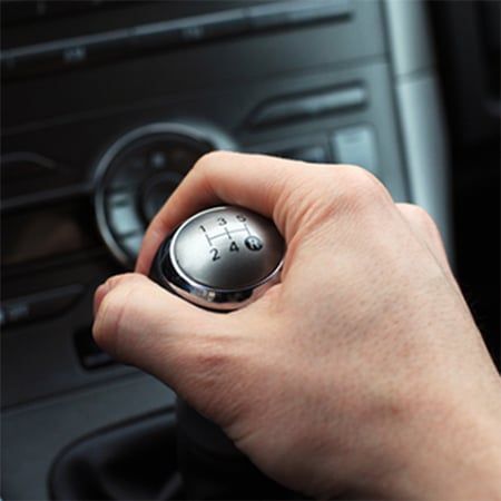 Hand on a car's gear stick, shifting between gears 1 to 5.