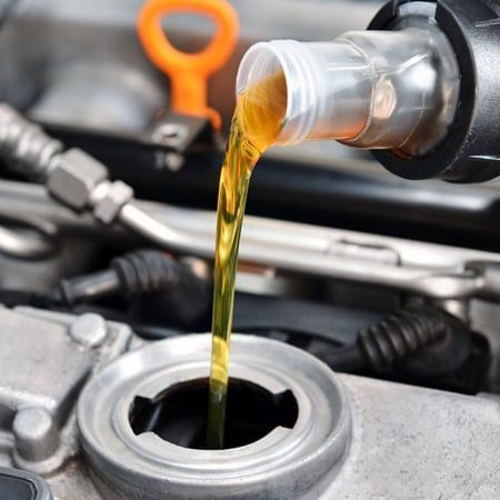 Oil being poured from a bottle into a car engine, highlighting maintenance.