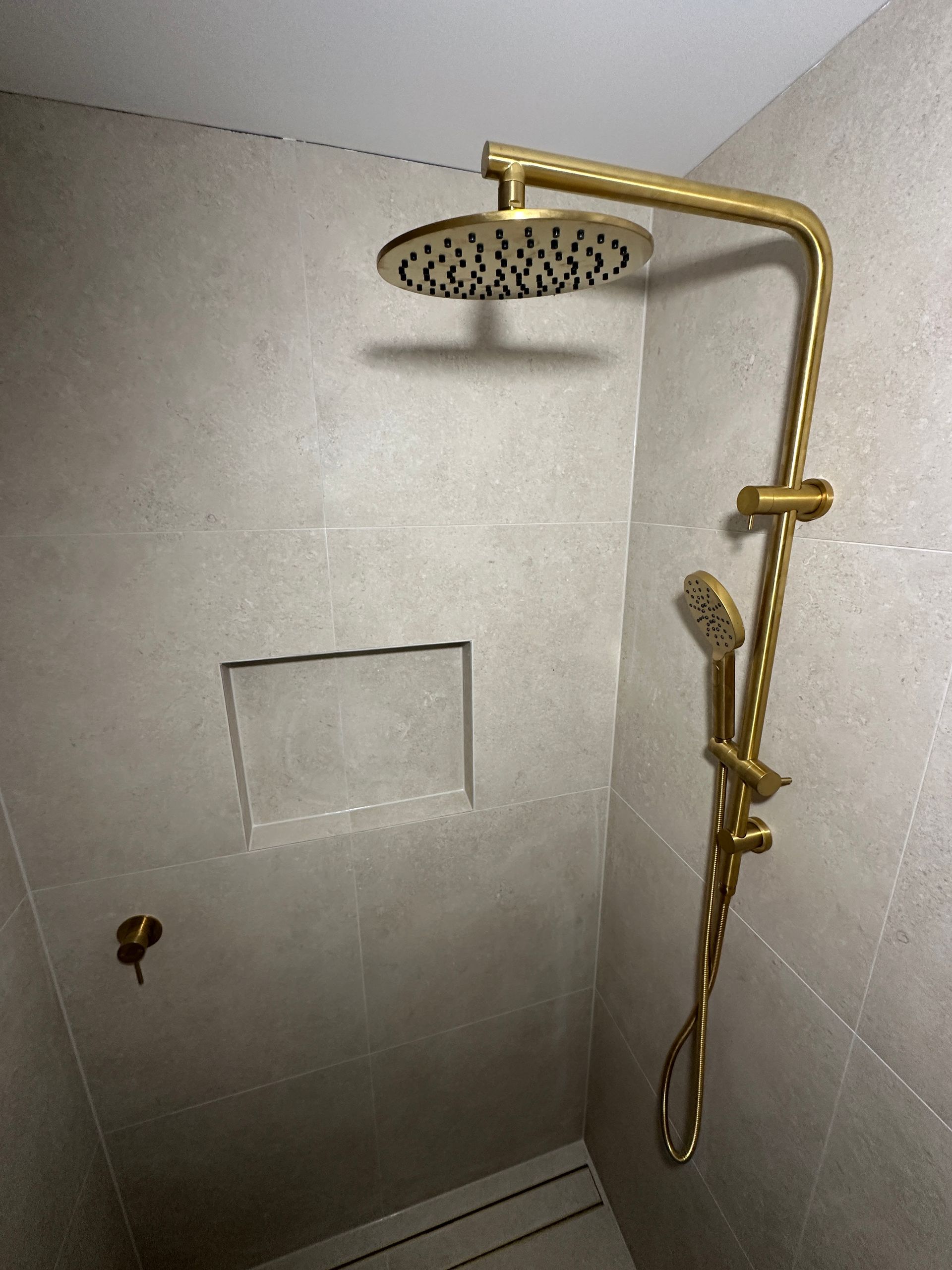 Gold Shower Fixtures Against Beige Tiled Wall With Recessed Niche — Vantage Plumbing and Drainage In Pacific Pines, QLD