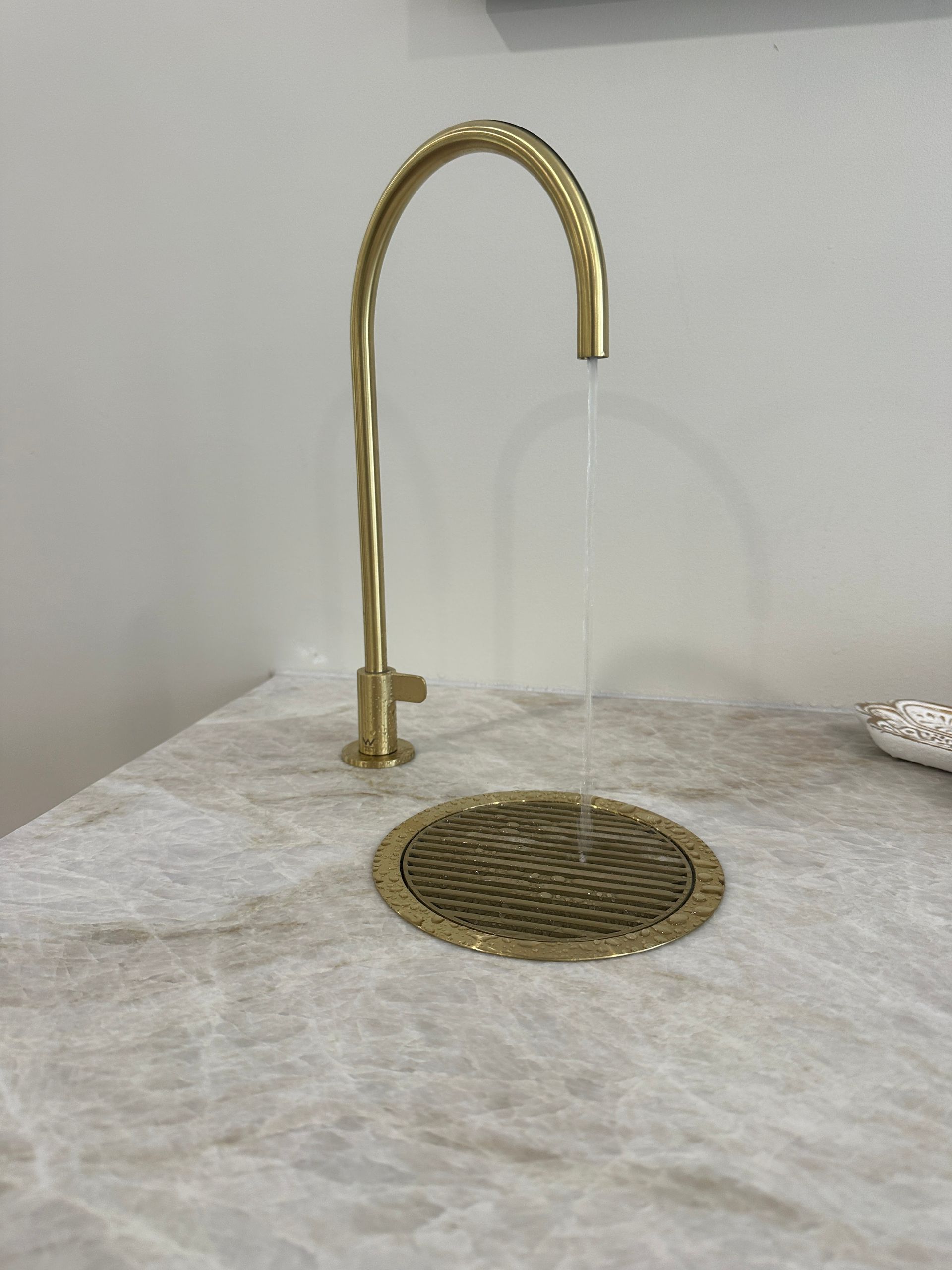 Gold Faucet With Water Flowing Into a Textured Drain on a Marble Countertop — Vantage Plumbing and Drainage In Oxenford, QLD