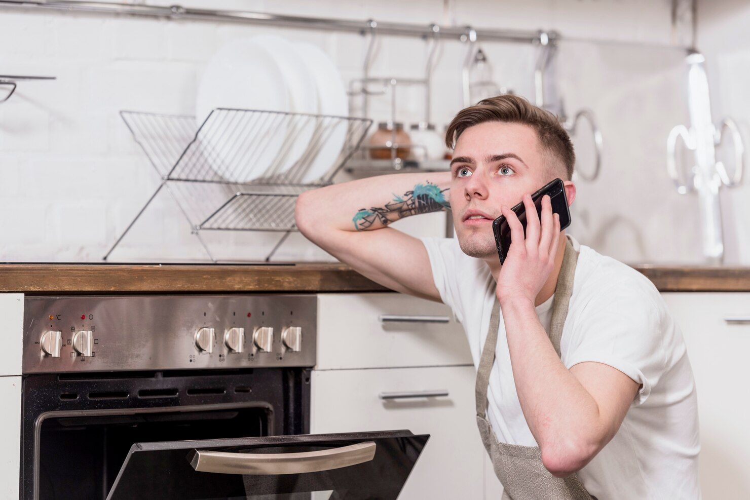 Man in Kitchen on Phone, Looking Up — Vantage Plumbing and Drainage In Pacific Pines, QLD