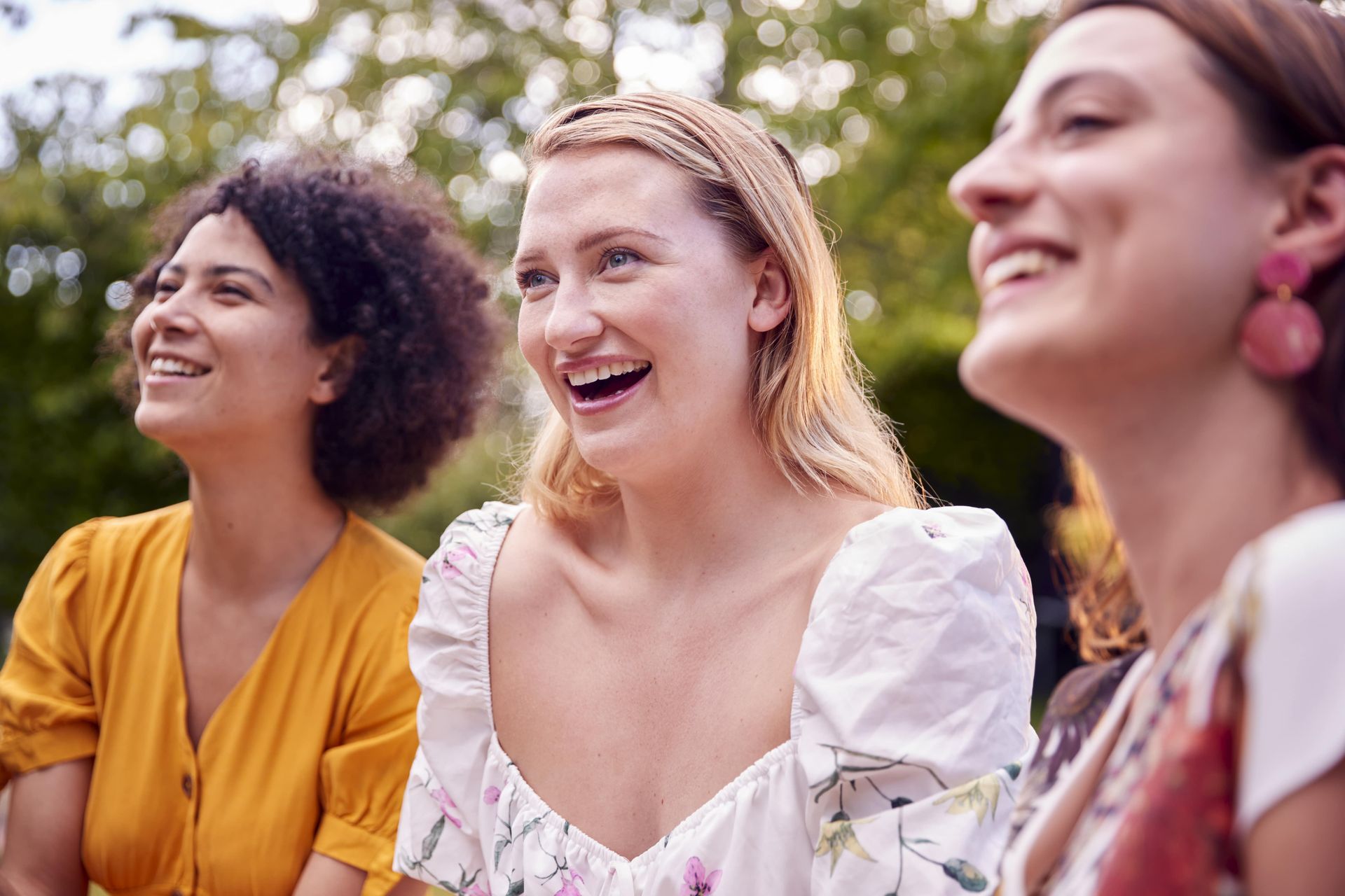 Three women are sitting next to each other and smiling.