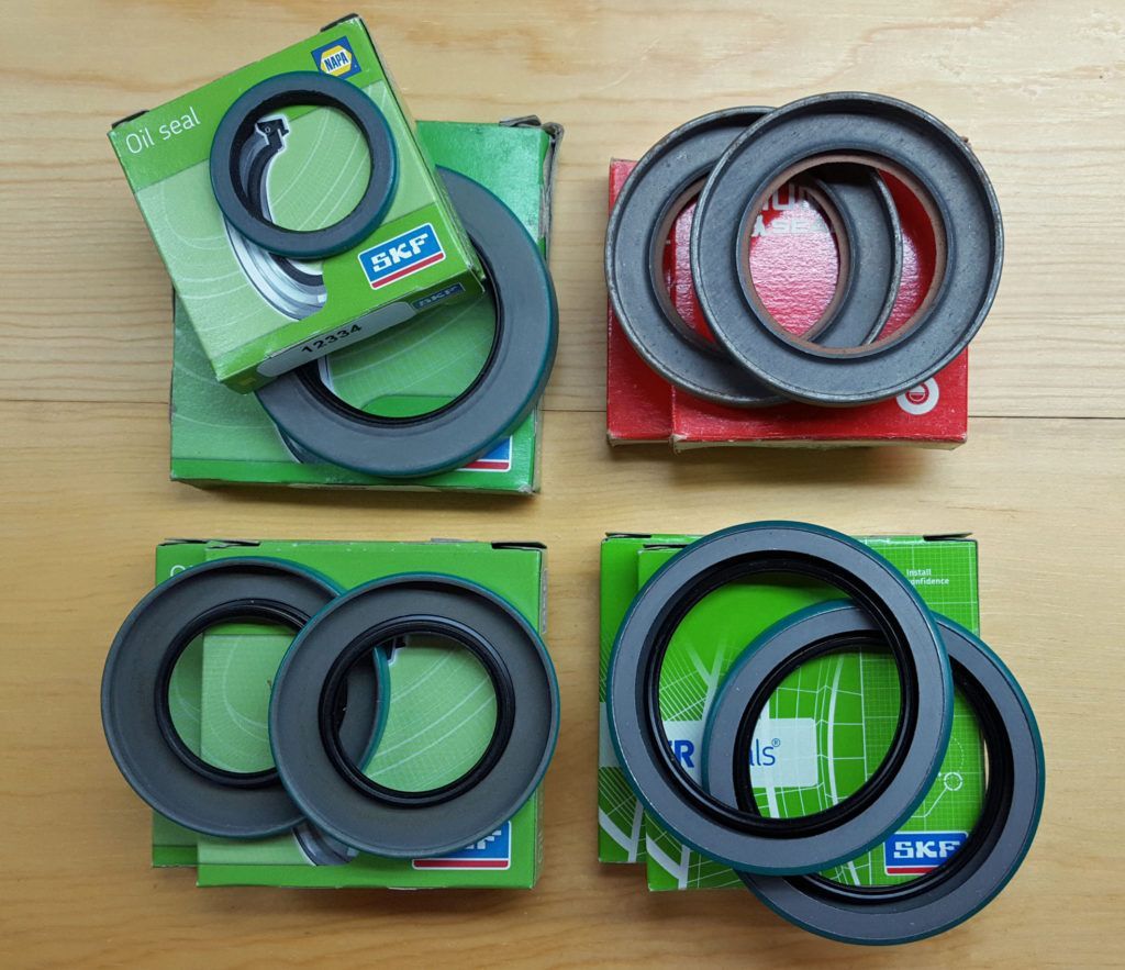 Four stacks of circular rubber seals, some in green and red boxes, on a wooden surface.