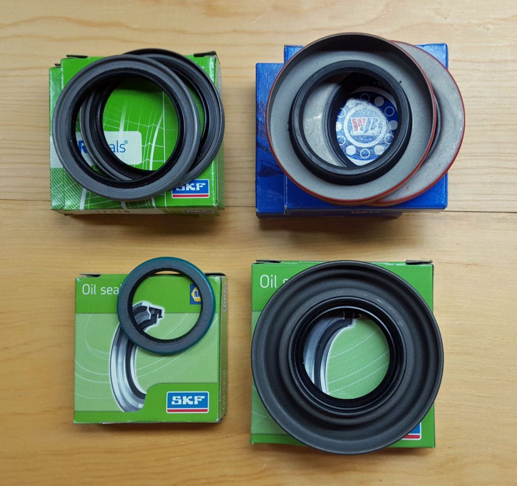 Four SKF brand oil seals in their boxes, arranged on a wooden surface. They are green and blue.