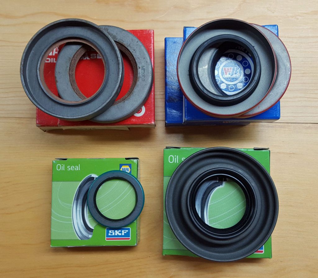 Four boxes of car seals, each with a circular seal on top. Different colors: red, blue, and green. Seals are black or gray.