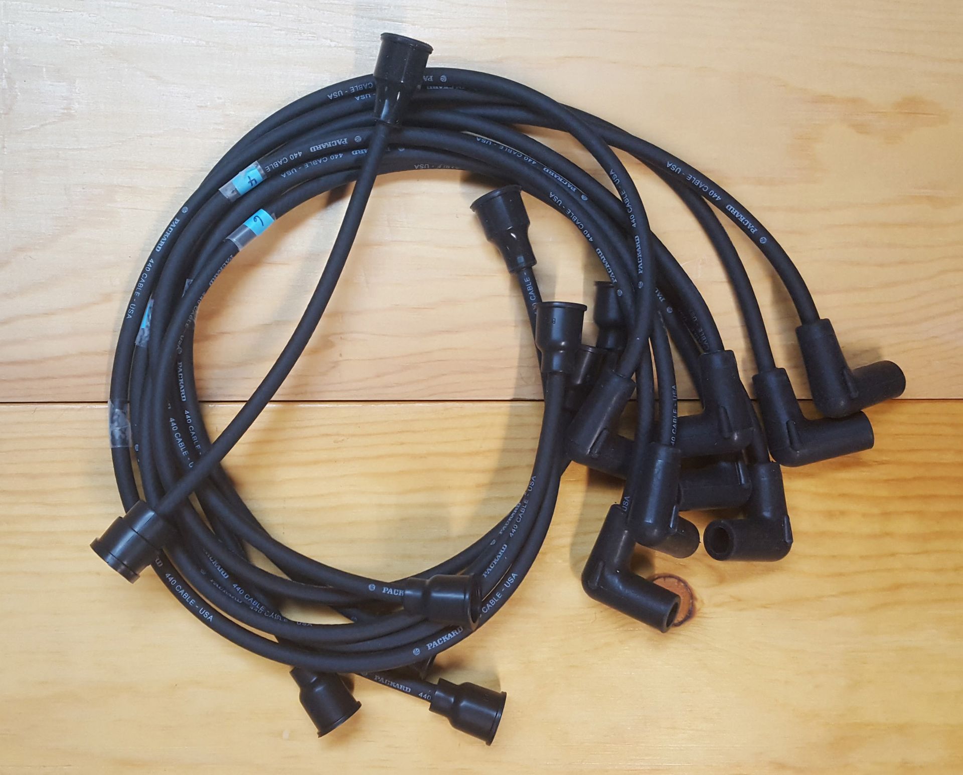 A bundle of black spark plug wires coiled on a wooden surface.