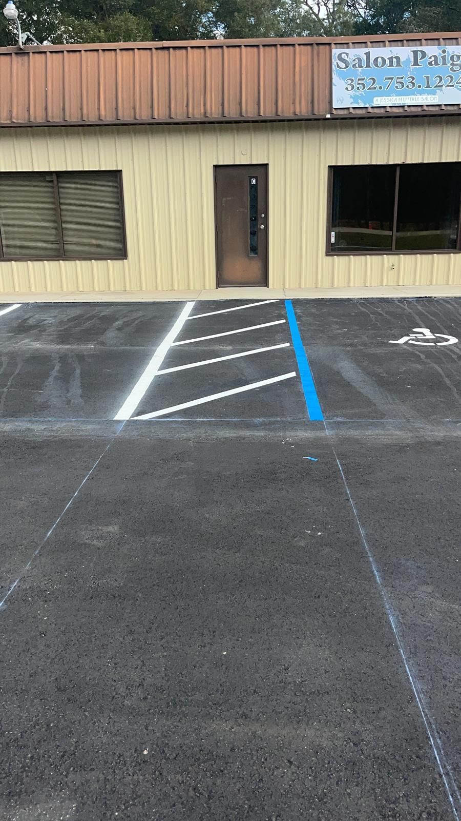 Empty accessible parking space with blue lines in front of a beige building entrance