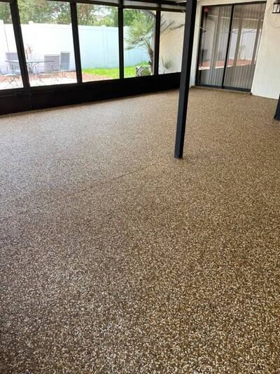 Empty indoor room with speckled carpet, black column, and large windows overlooking a patio and yard
