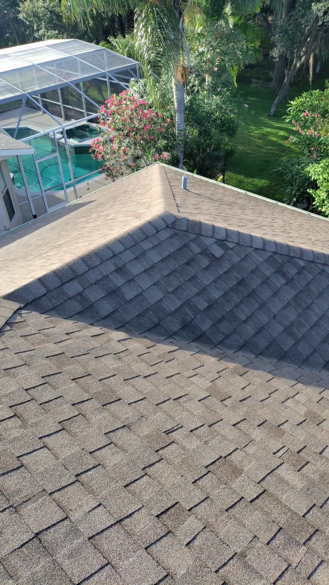 Shingled rooftop overlooking a backyard with a covered pool and green trees