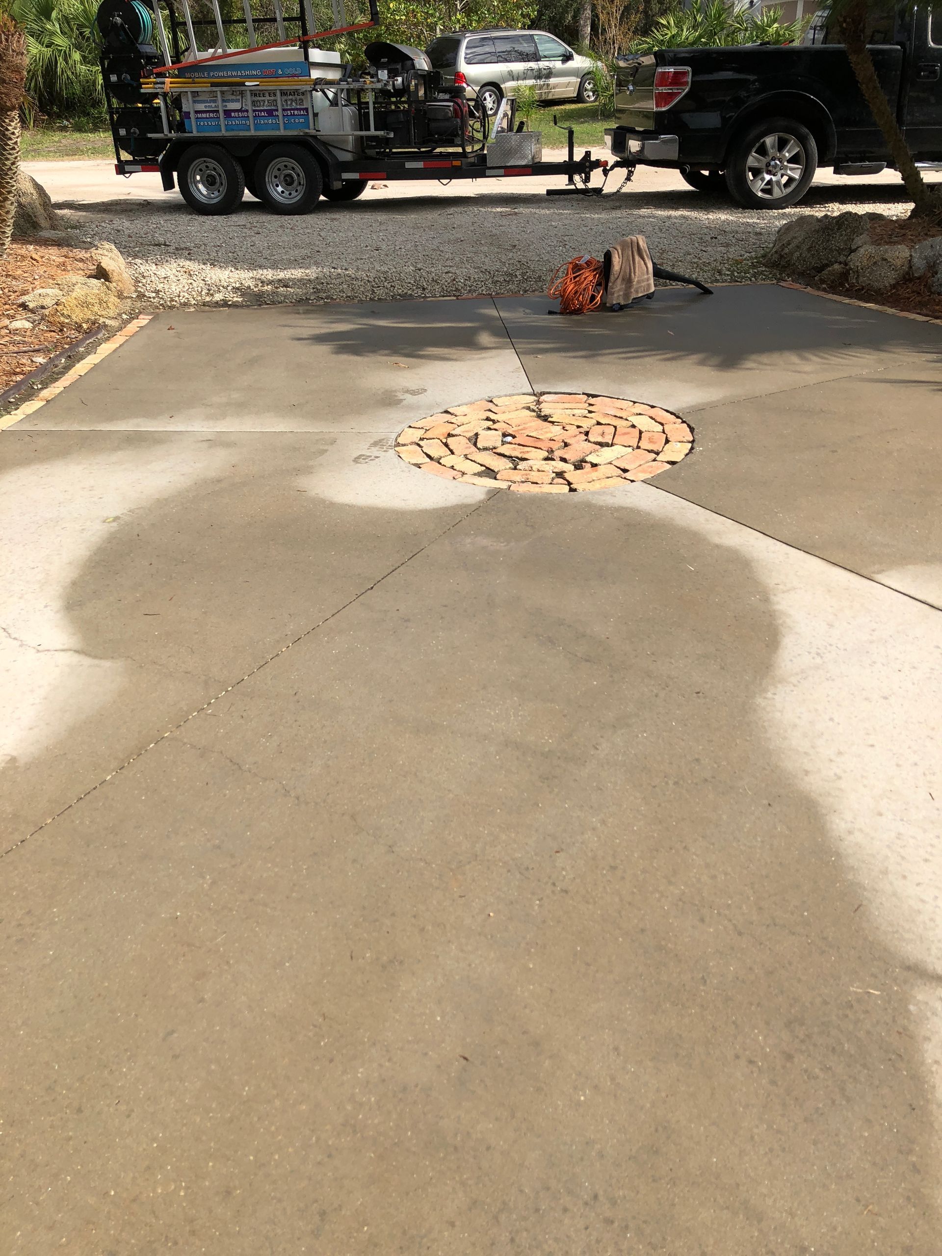 Driveway with a circular patch and a small landscaping trailer in the background