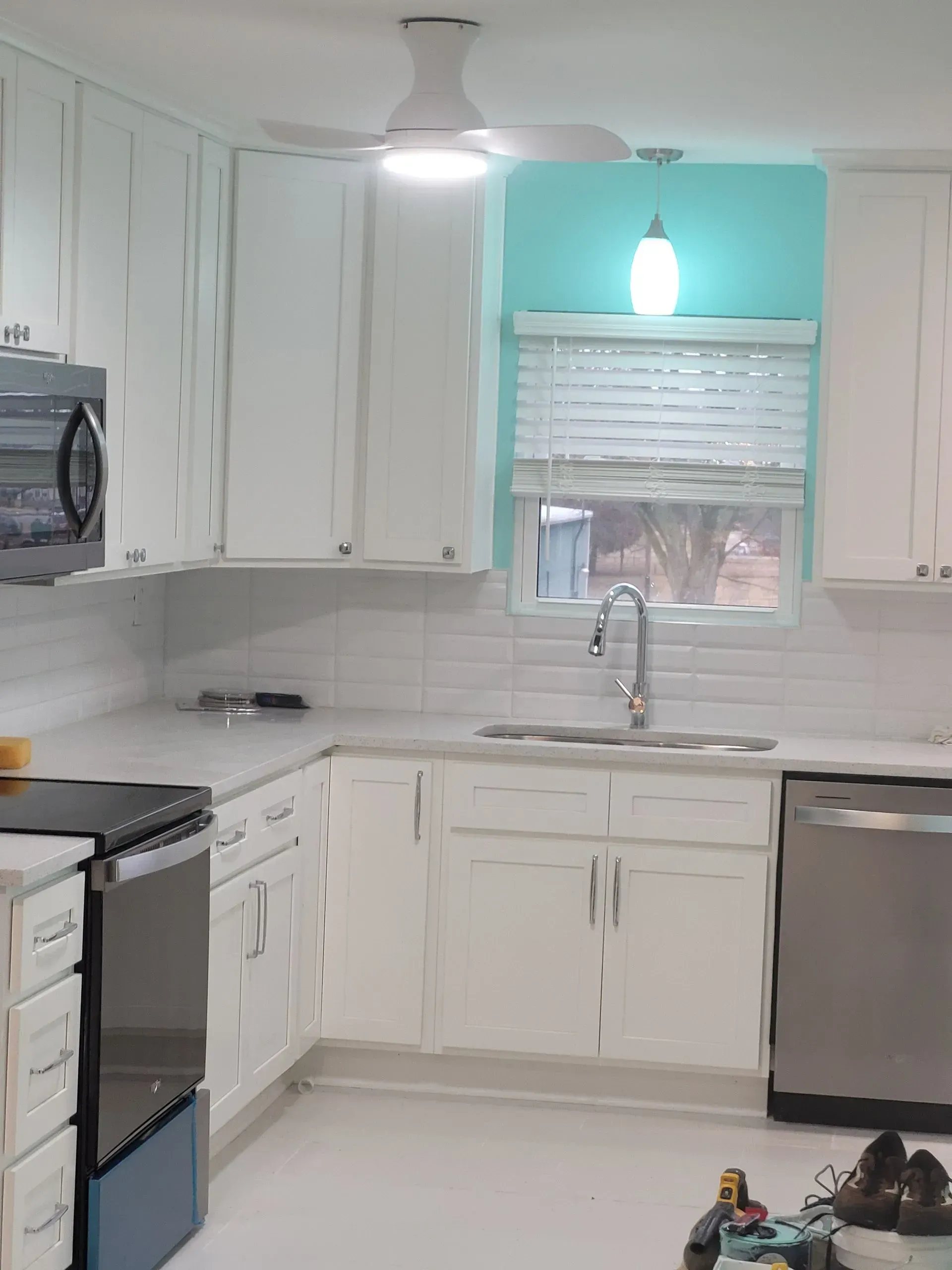 White kitchen with teal accent wall and light. Stainless steel appliances.