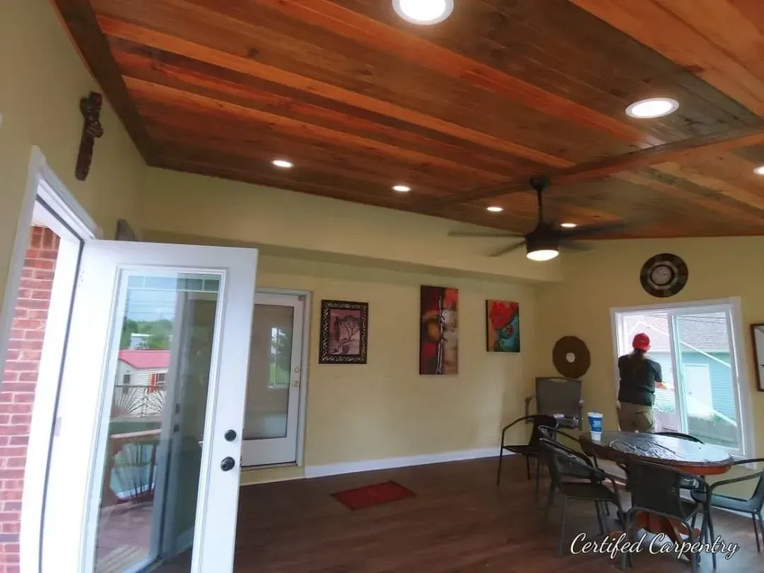An interior room with a wooden ceiling, glass doors, and a person at a window.