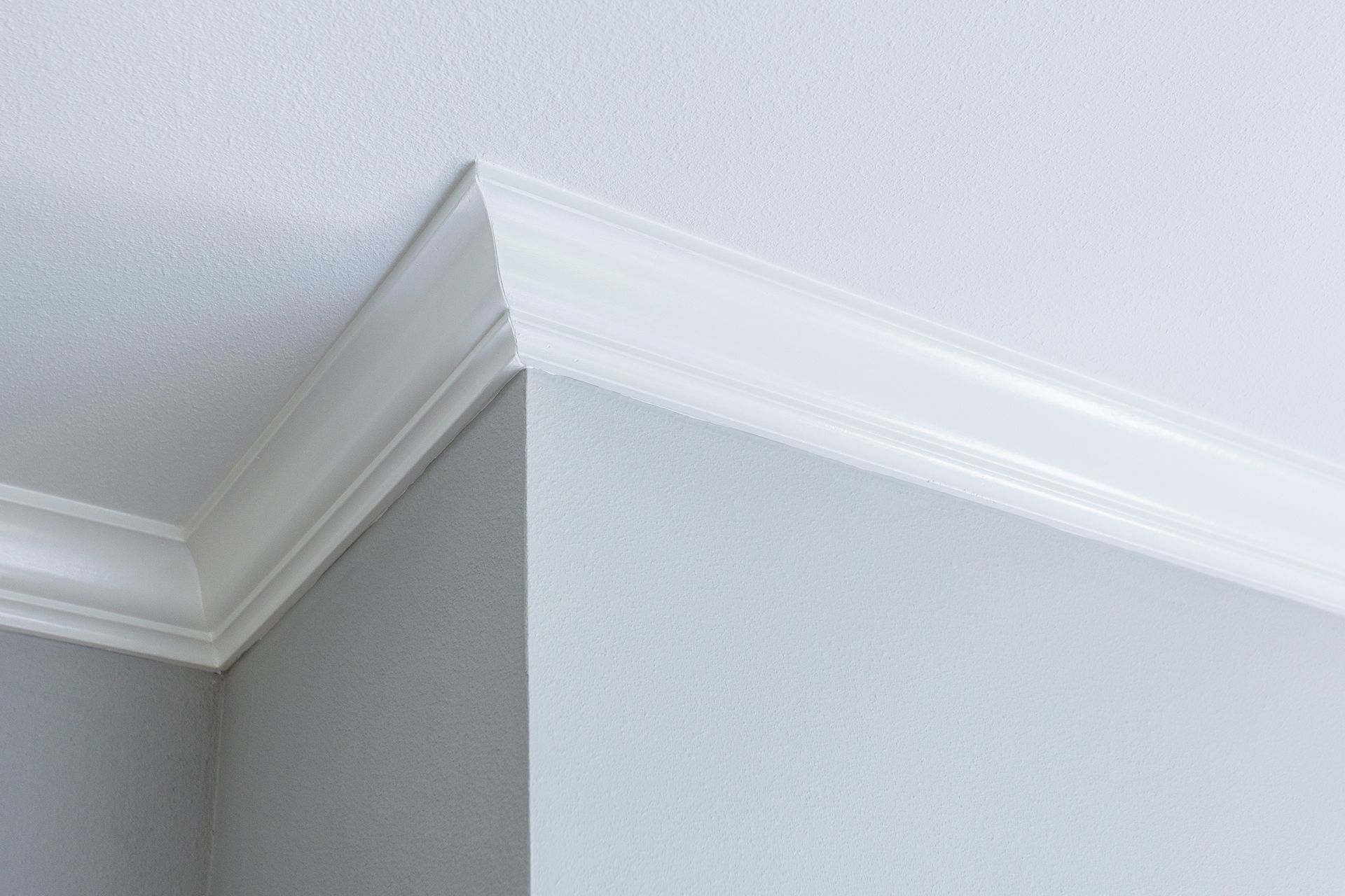 White crown molding at a corner where the ceiling meets gray and white walls.
