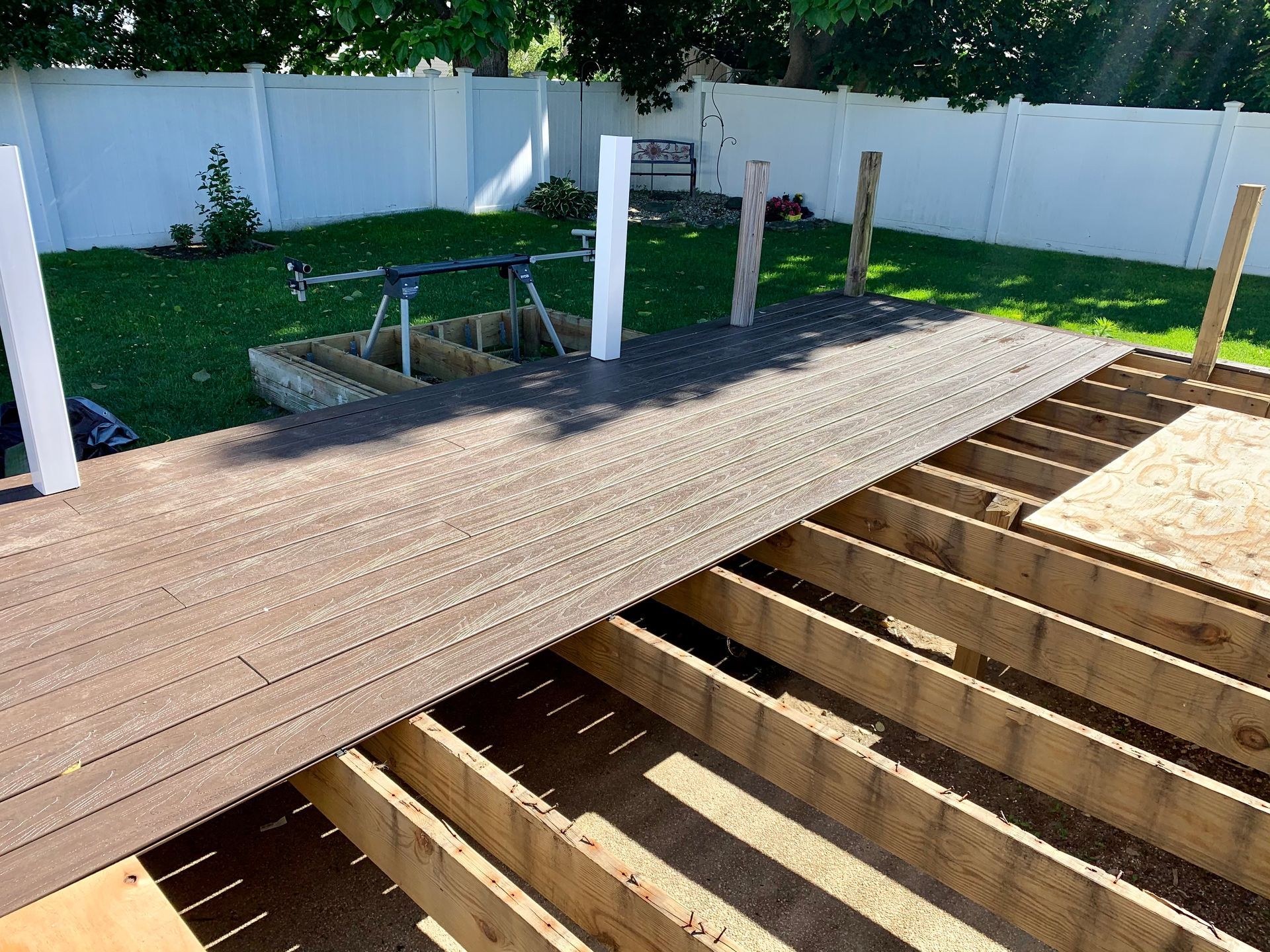 Wooden deck under construction; brown planks being laid over the frame in a backyard.