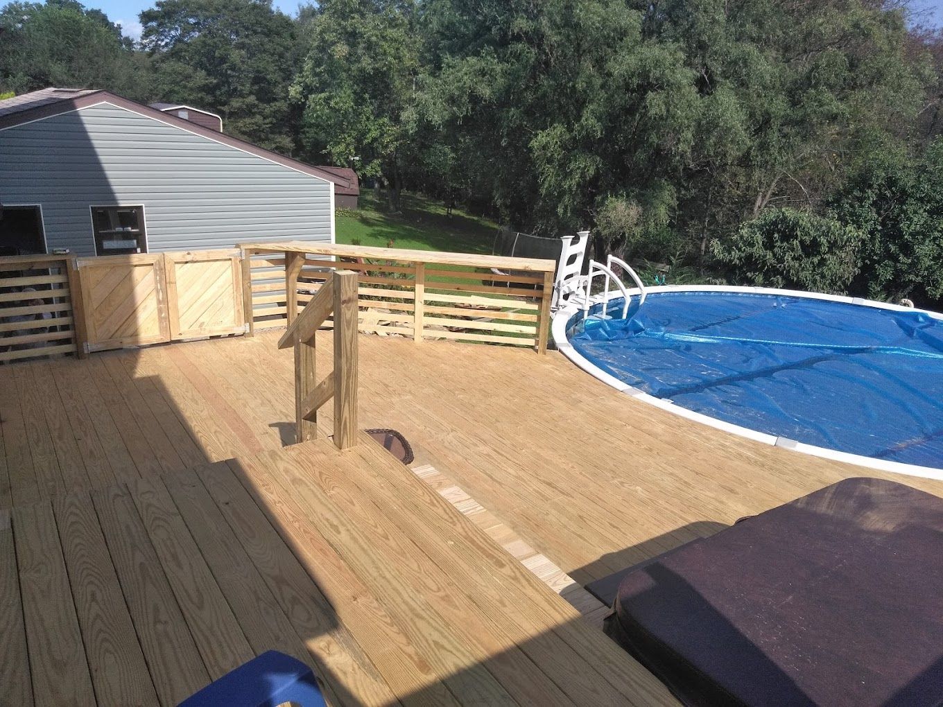 A wooden deck with a swimming pool in the background