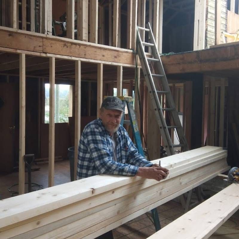 A man in a plaid shirt is leaning on a wooden beam