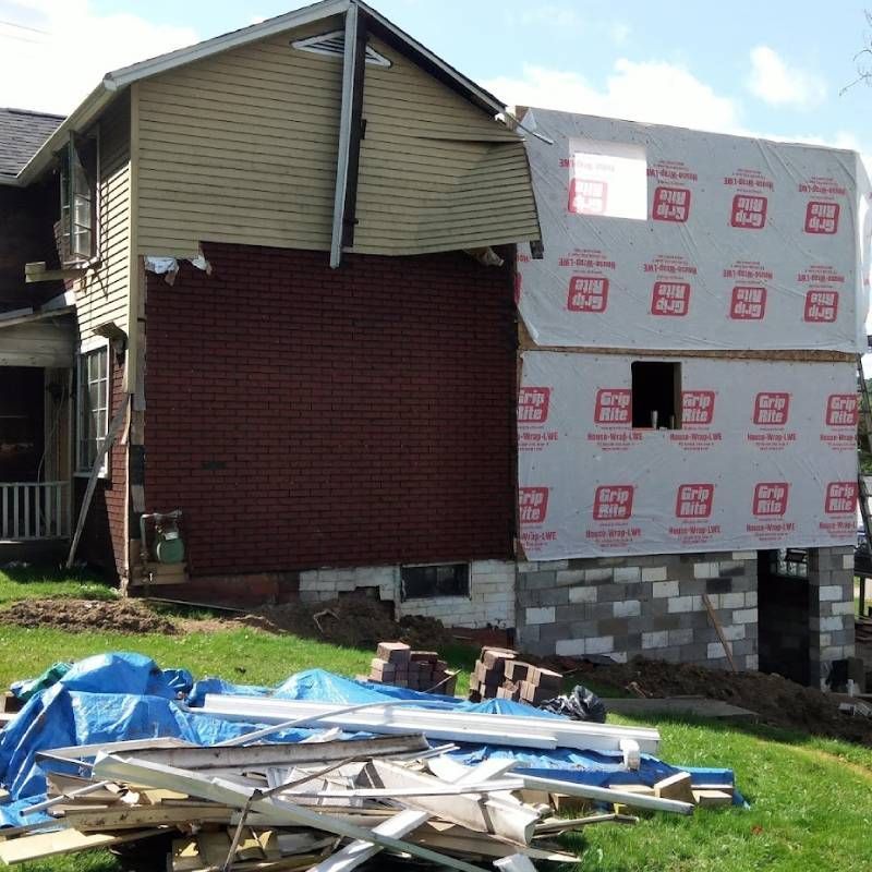 A house that is being remodeled with a stack of wood in front of it