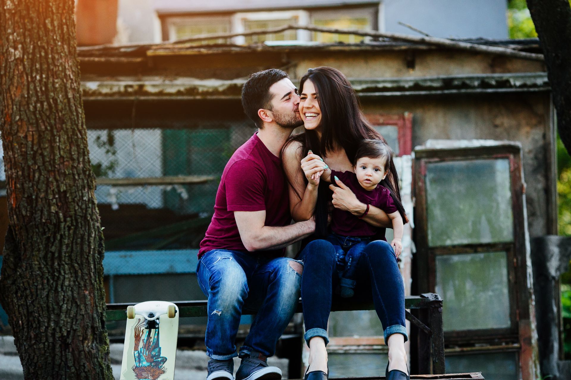 A man is kissing a woman on the cheek while holding a baby.