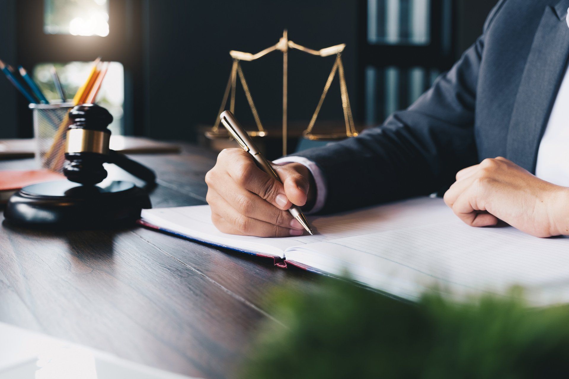 A lawyer is sitting at a desk writing in a notebook.