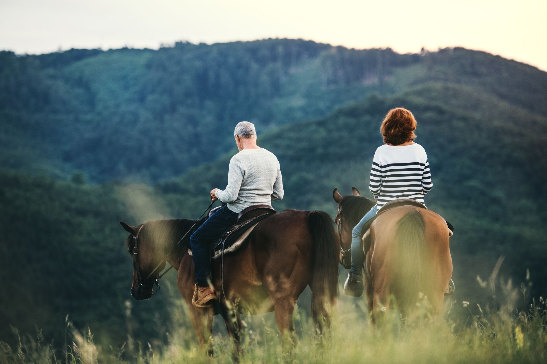 A man and a woman are riding horses in a field.