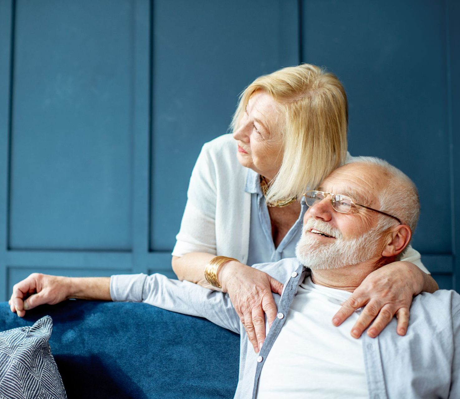 A woman is hugging an older man on a couch.
