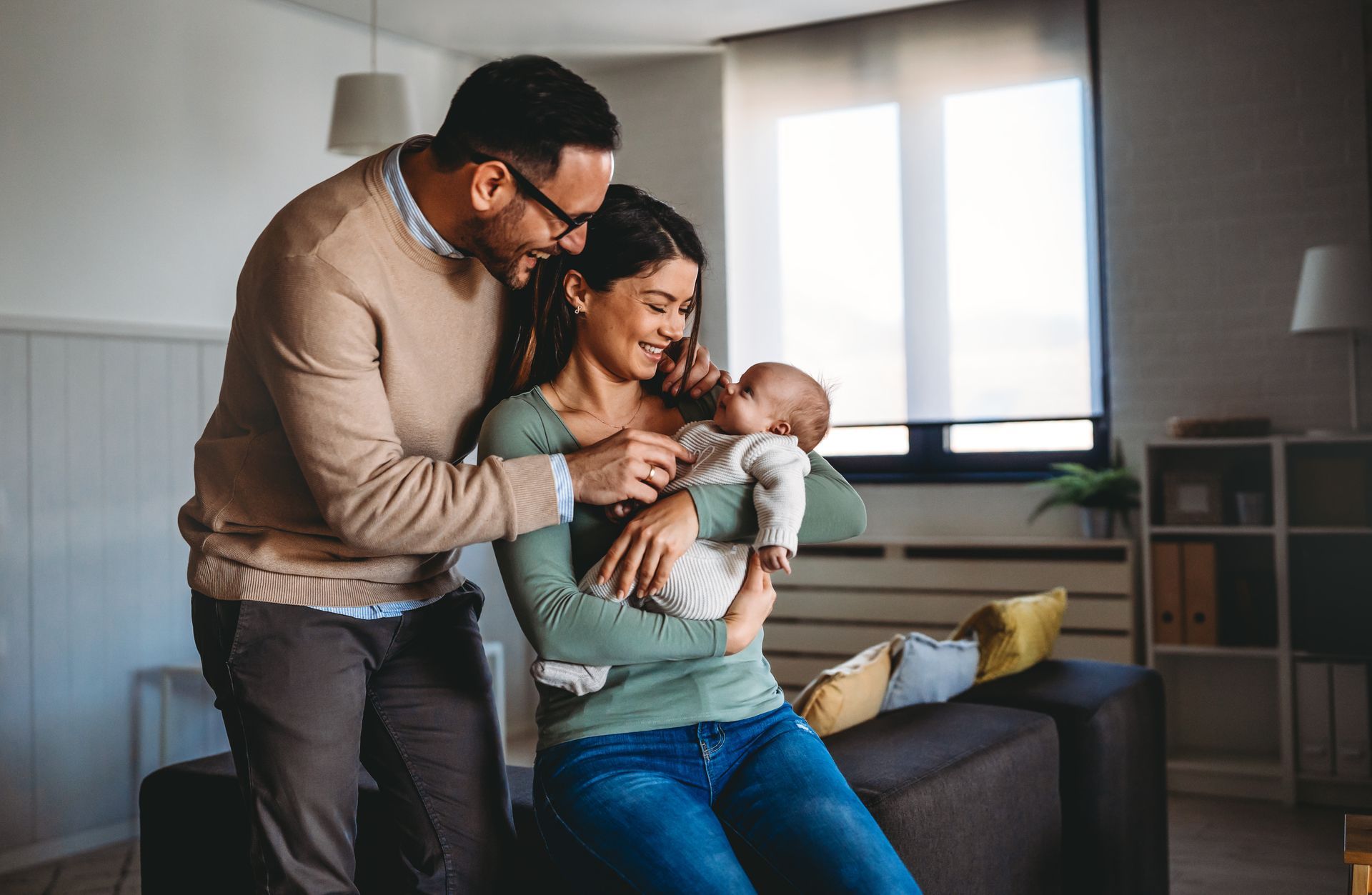 A man and woman are holding a baby while sitting on a couch.