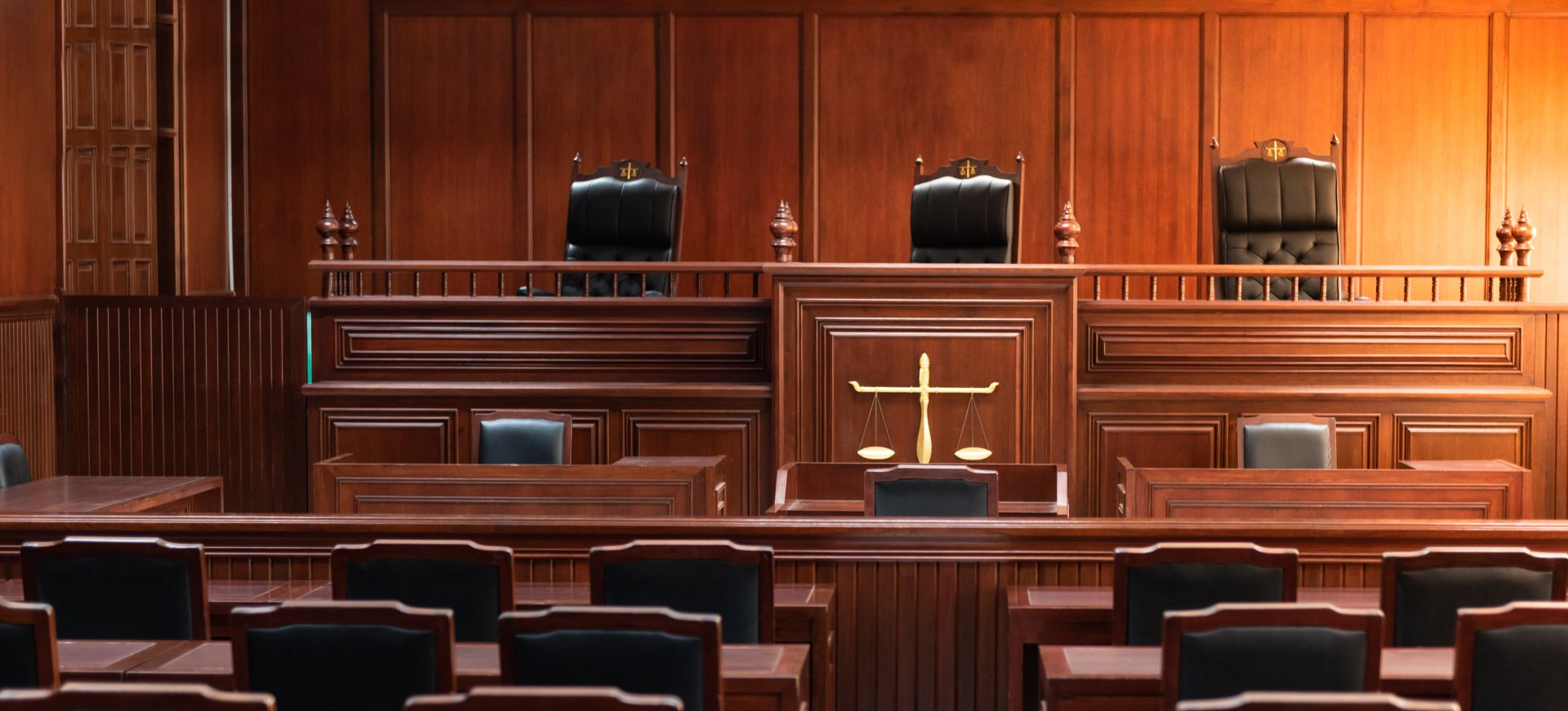An empty courtroom with a judge 's bench and chairs.