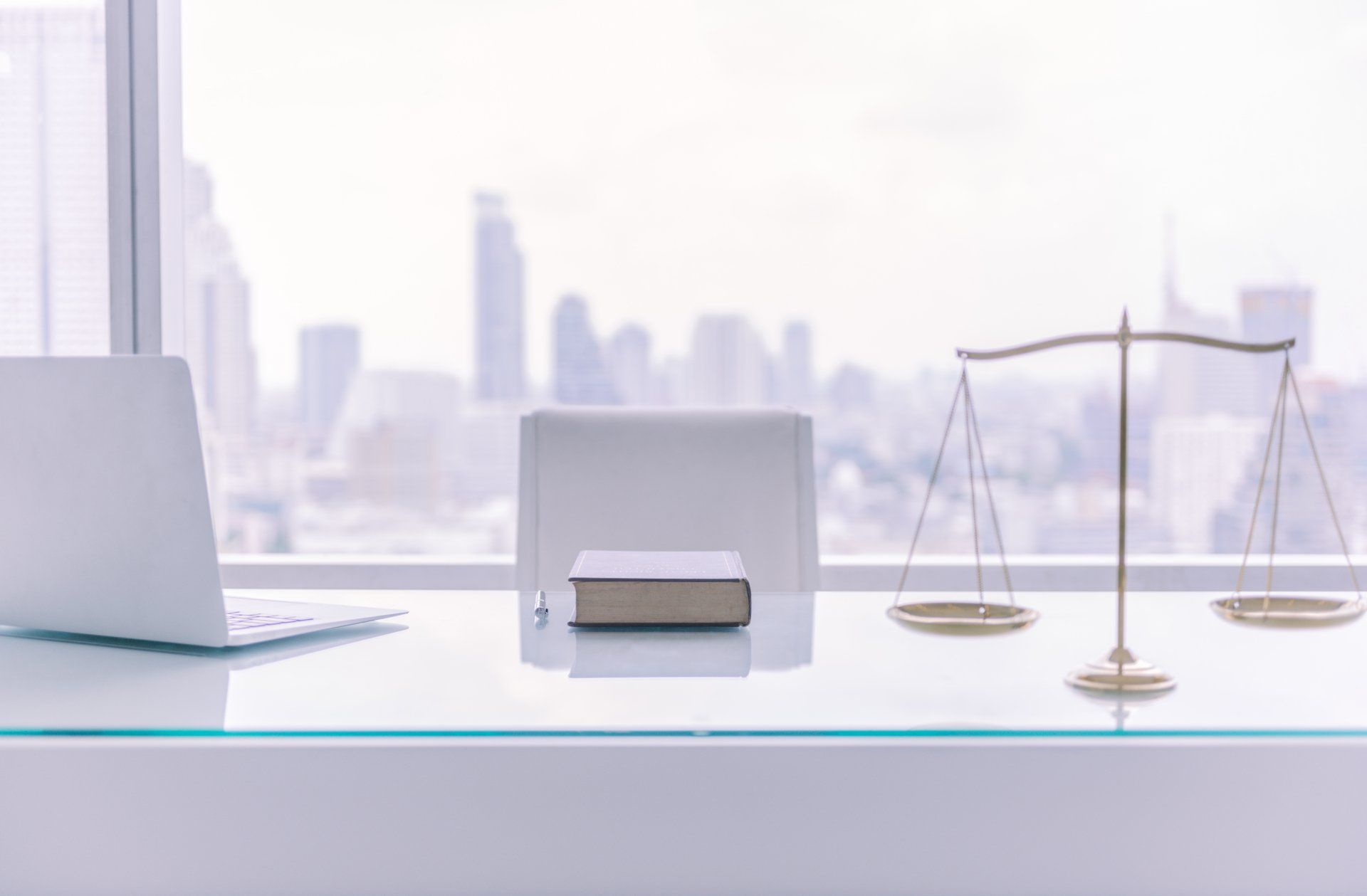 A desk with a laptop , book , scales of justice and a book on it.