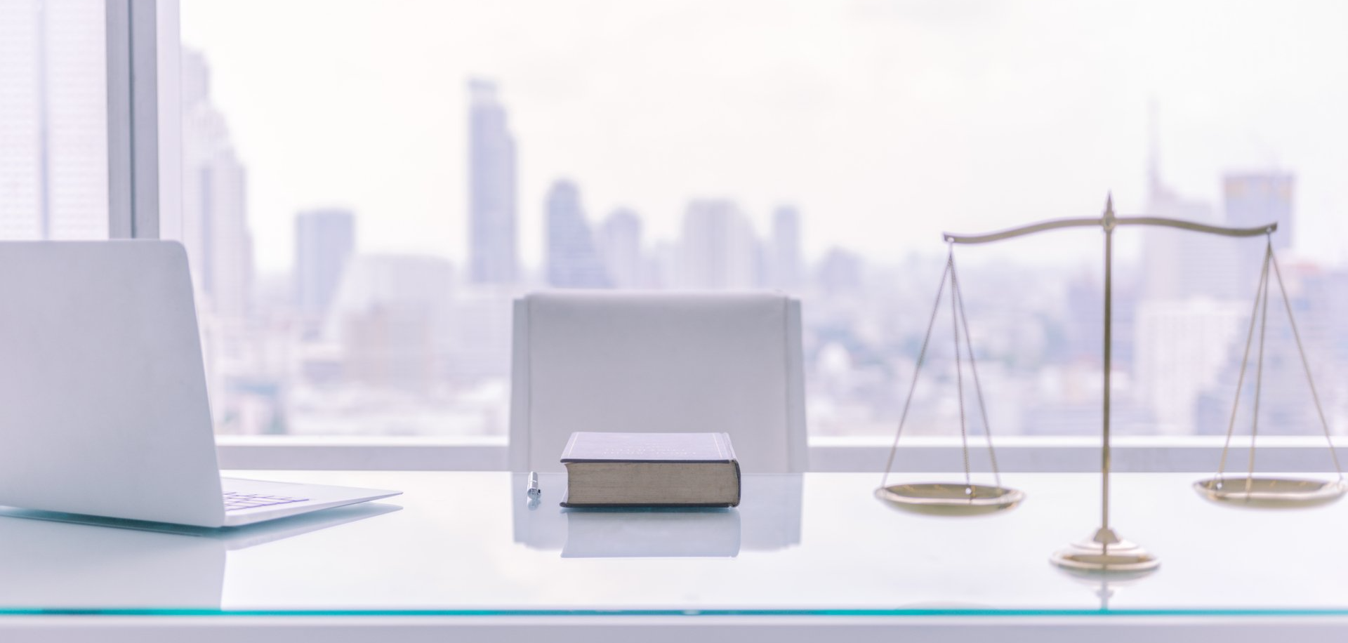 A desk with a book , scales of justice , and a laptop.