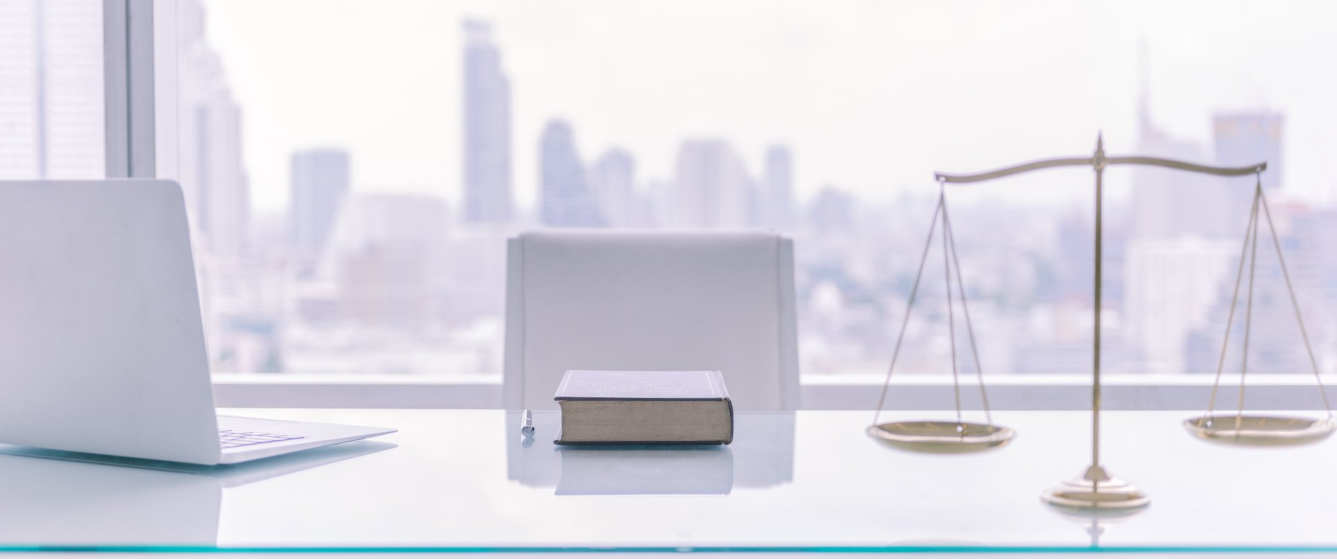 A desk with a laptop , book , scales of justice and a book on it.