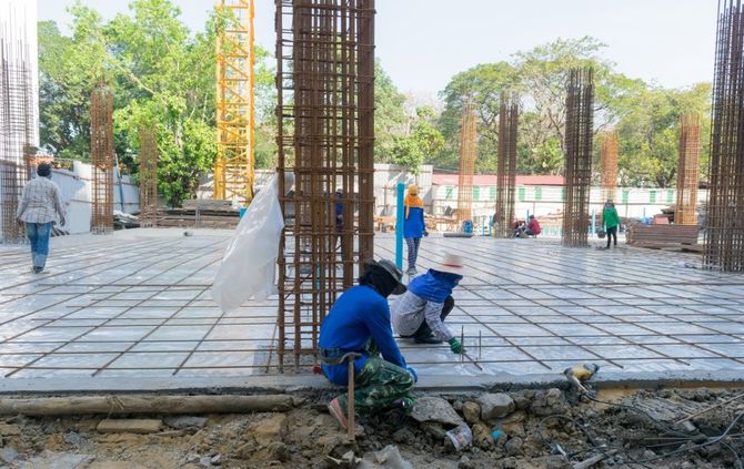 Workers laying concrete around rebar columns at a construction site