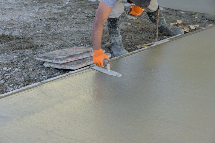 Worker smoothing wet concrete with a trowel on a construction site