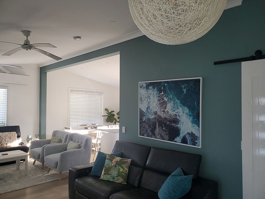 A Living Room with a Black Couch and a Picture on the Wall — JWP Painting & Property Services in Gosford, NSW