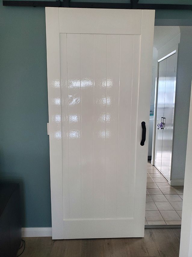 A White Sliding Barn Door is Open in a Living Room — JWP Painting & Property Services in Ettalong Beach, NSW