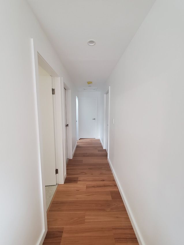 A Long Hallway with Wooden Floors and White Walls — JWP Painting & Property Services in Newcastle, NSW