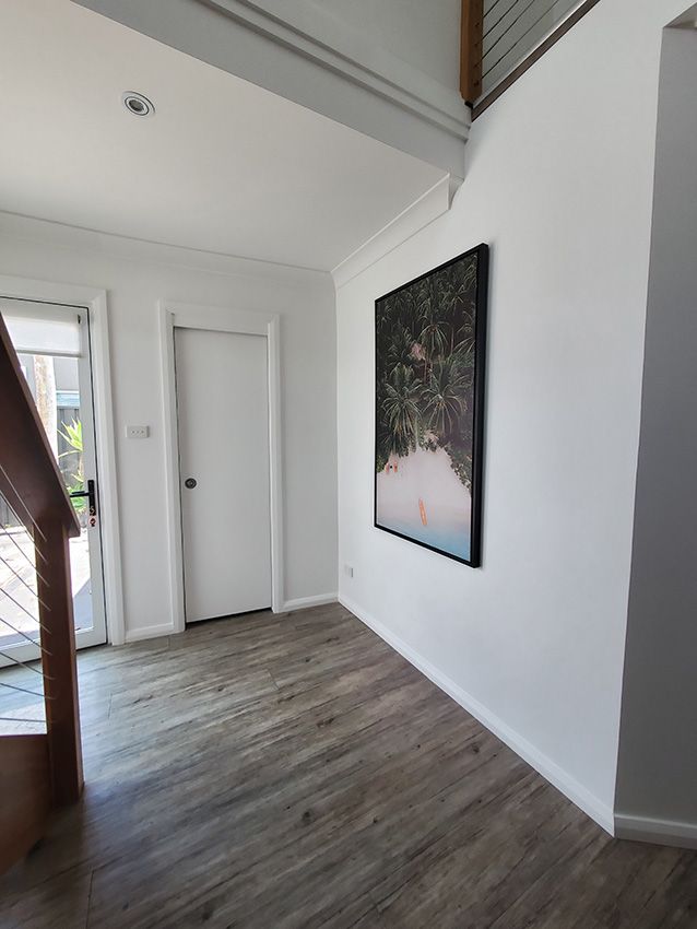 A Hallway with Wooden Floors and a Painting on the Wall — JWP Painting & Property Services in Ettalong Beach, NSW