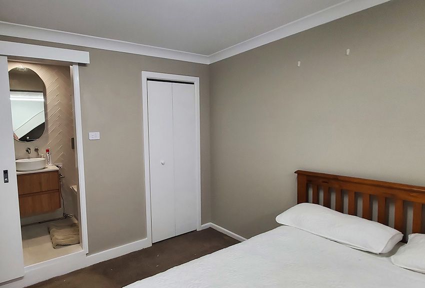 A Bedroom with a Bed, Bathroom, Sink and Mirror — JWP Painting & Property Services in Lake Macquarie, NSW