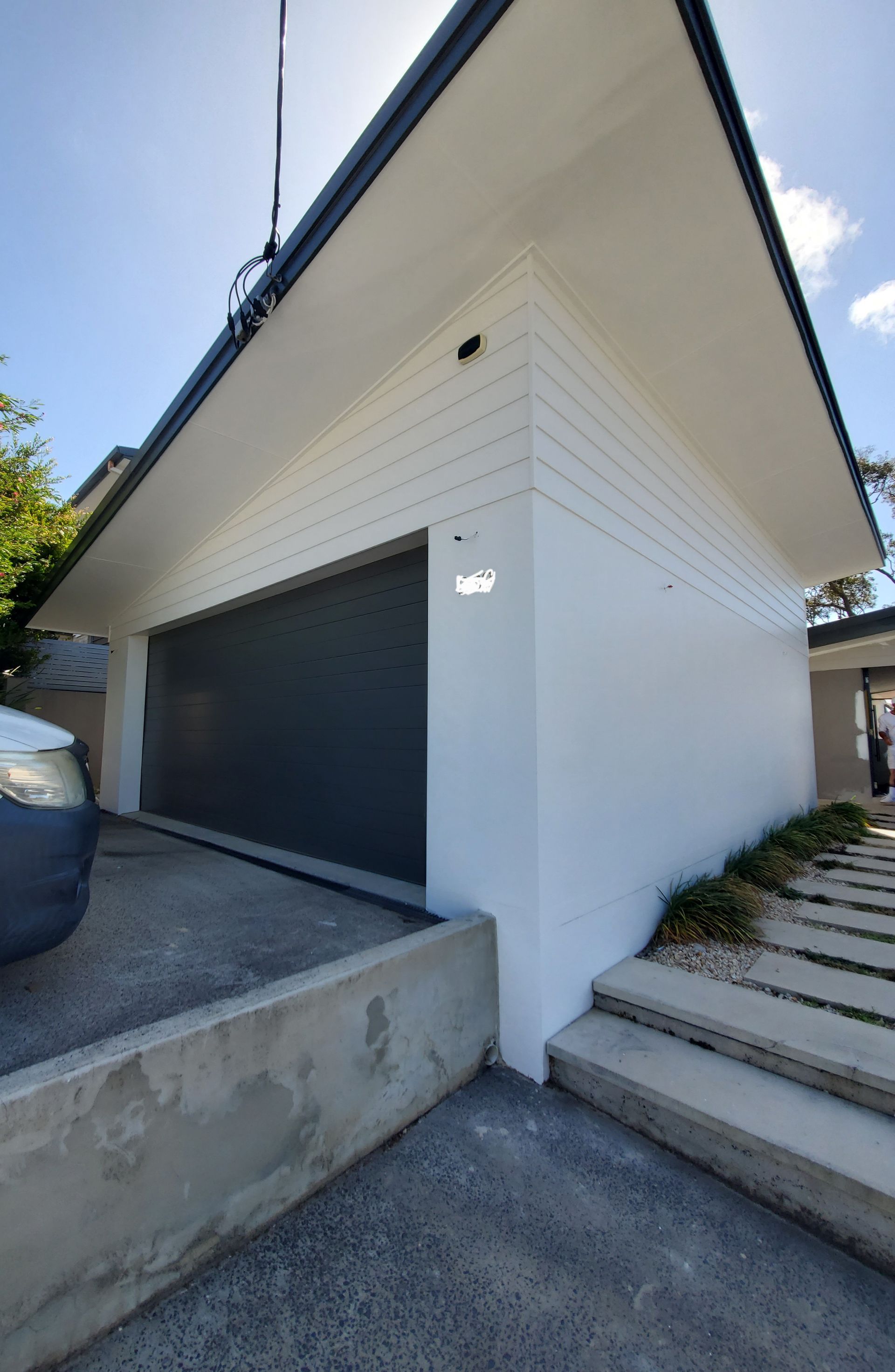 A Car is Parked in Front of a House With a Black Garage Door — JWP Painting & Property Services in Ettalong Beach, NSW
