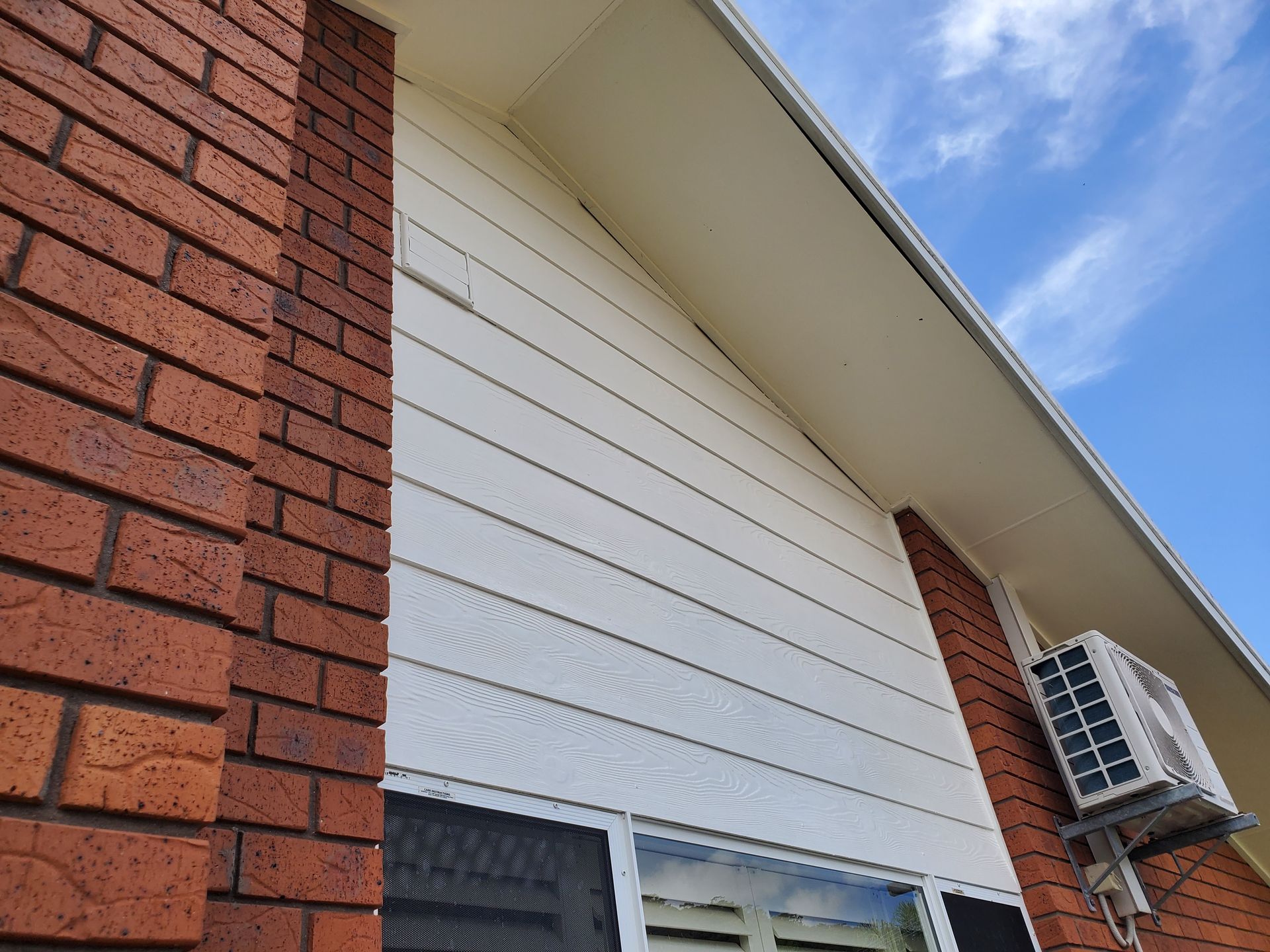 Brick Building Exterior With White Siding and Air Conditioner — JWP Painting & Property Services in Ettalong Beach, NSW