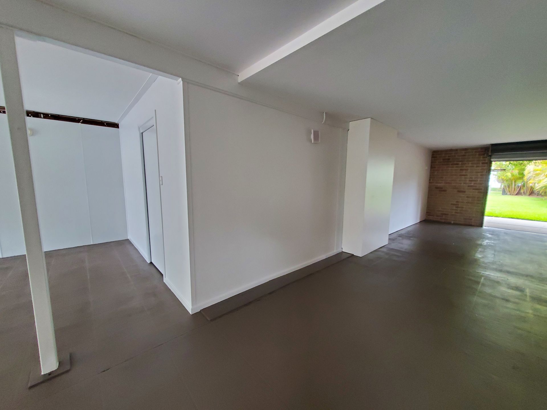 A Large Empty Room With White Walls and a Concrete Floor — JWP Painting & Property Services in Ettalong Beach, NSW