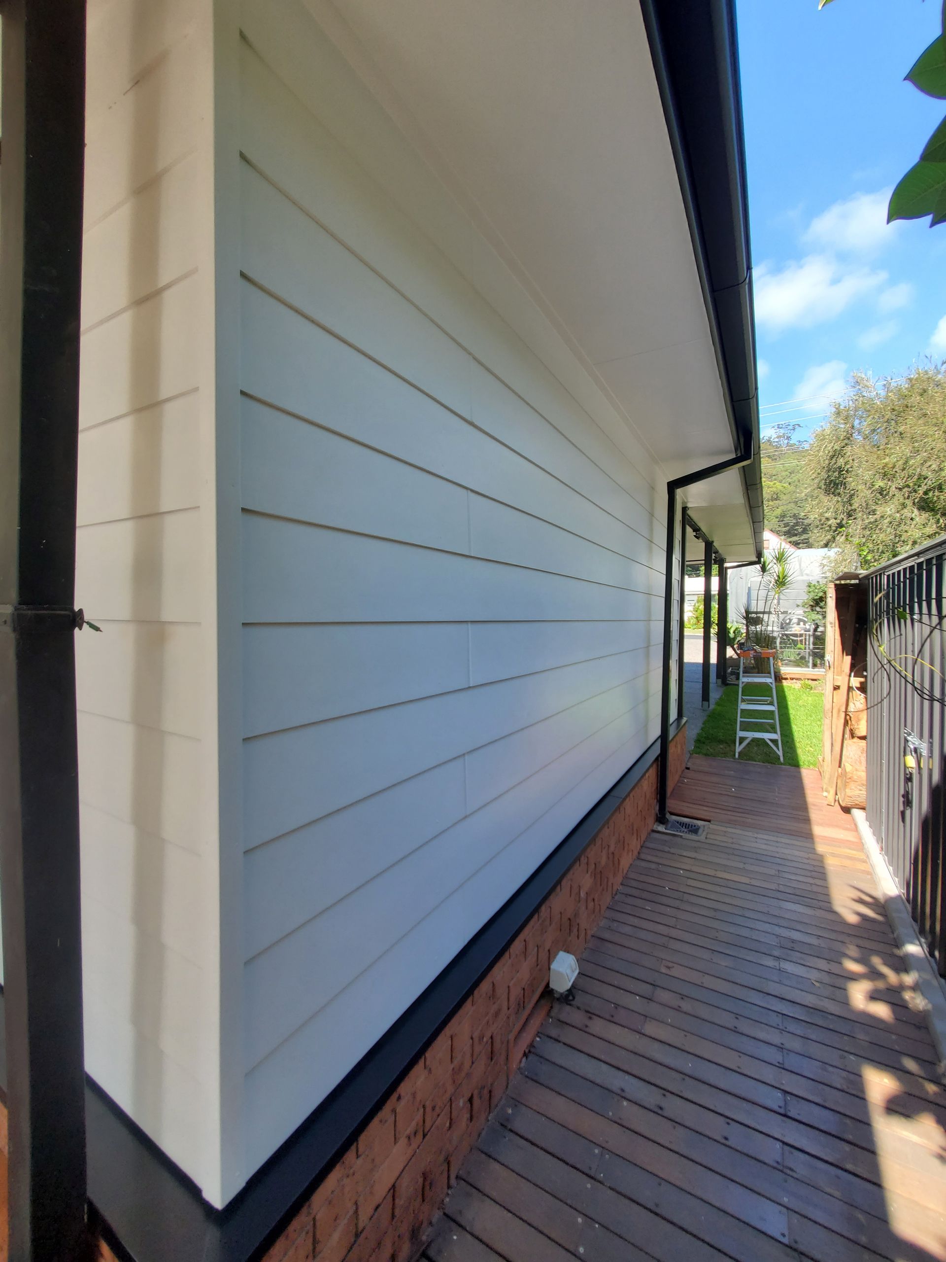 Side View of a House With White Siding, Dark Trim, and a Brick Base — JWP Painting & Property Services in Ettalong Beach, NSW