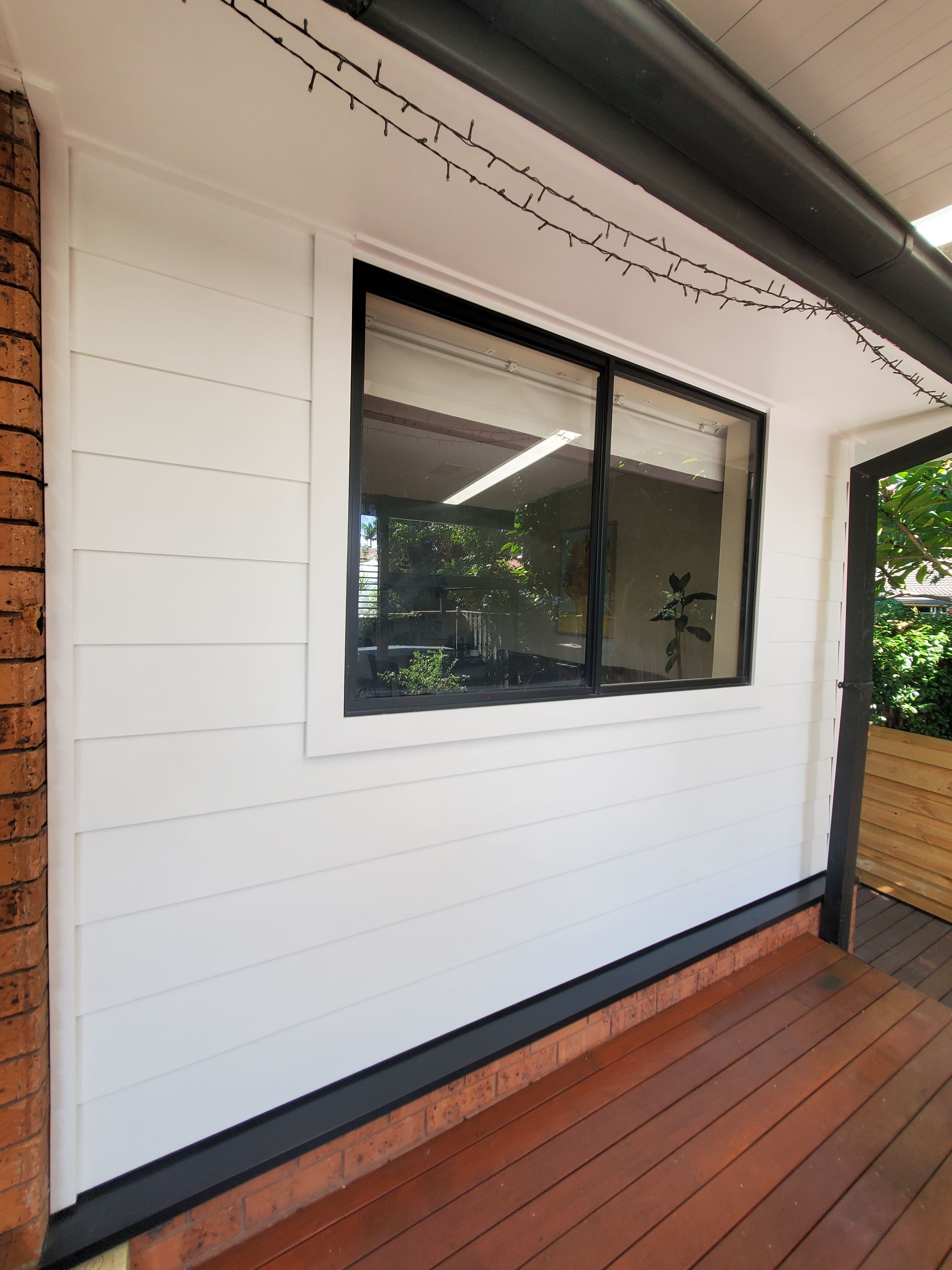 A White House With a Large Window and a Wooden Deck — JWP Painting & Property Services in Ettalong Beach, NSW