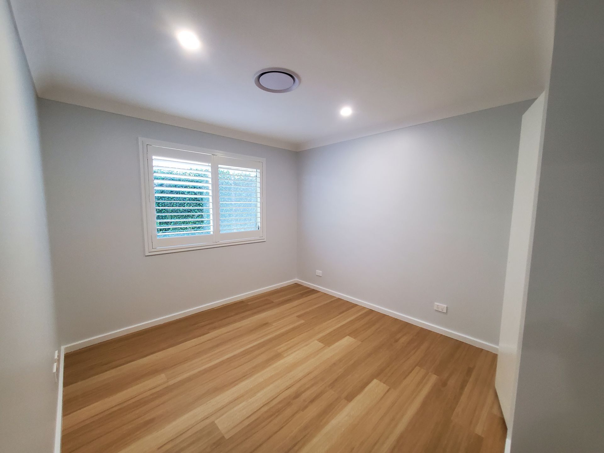 An Empty Room With Hardwood Floors and Shutters on the Windows — JWP Painting & Property Services in Ettalong Beach, NSW